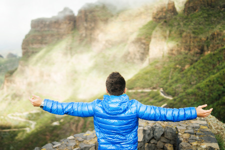 Man in blue jacket relaxing in the mountains with cloudy skyの写真素材