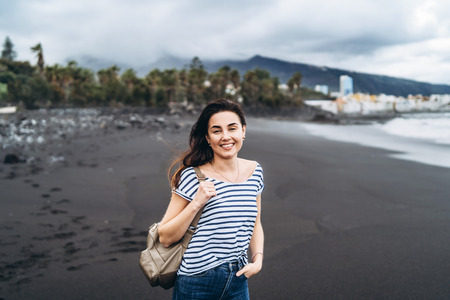Pretty brunette girl walking on the black sand beachの写真素材