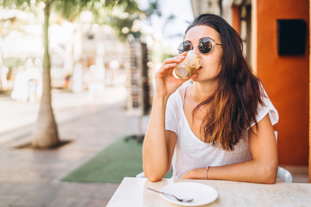 Pretty long hair brunette girl enjoy coffee in street cafeの写真素材