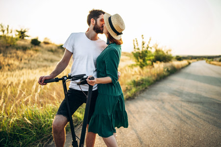 Young couple on vacation having fun driving electric scooter on the road in the countryside. Content technologies. Back view.の写真素材