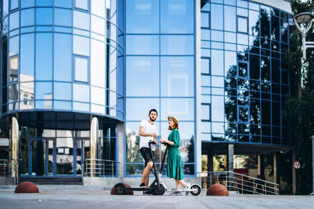 Young couple on vacation having fun driving electric scooter on the road in the countryside. Content technologies. Back view.の写真素材