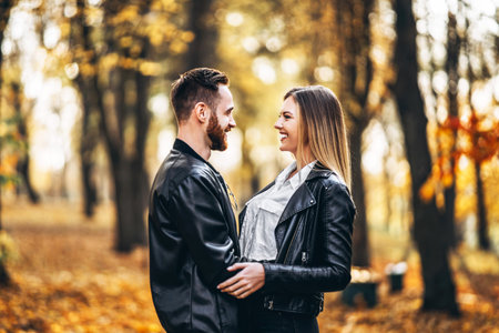 Sunny portrait of a young loving couple walking in the autumn park. They hug and smile, enjoy a walk.の写真素材