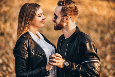 Sunny portrait of a young loving couple walking in the autumn park. They hug and smile, enjoy a...