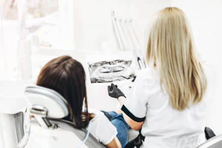 Dentist showing x-ray for the patient and explaining plan of treatmentの写真素材
