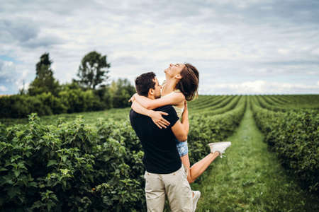A tender loving couple walking in a field of currant. Man whirls woman in her arms. Love story.の写真素材