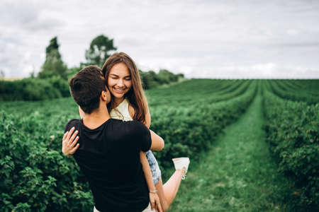 A tender loving couple walking in a field of currant. Man whirls woman in her arms. Love story.の写真素材