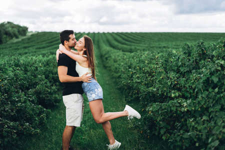 A tender loving couple walking in a field of currant. Man whirls woman in her arms. Love story.の写真素材