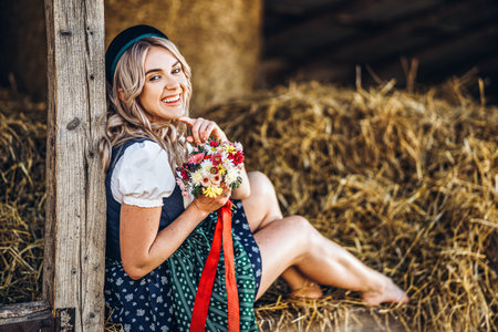 Pretty happy blonde in dirndl, traditional festival dress, holding two mugs of beer outdoors in the...