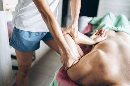 A woman physiotherapist doing massage for a man in the medical office. Closeup of hands doing massage.の写真素材