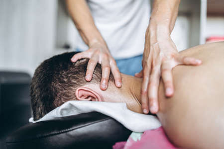 A woman physiotherapist doing massage for a man in the medical office. Closeup of hands doing massage.の写真素材