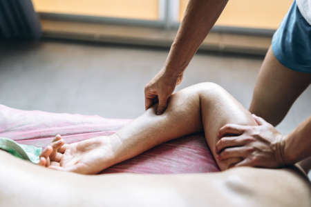 A woman physiotherapist doing massage for a man in the medical office. Closeup of hands doing massage.の写真素材