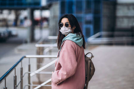 Female in medical mask outdoors in the empty city. Health protection and prevention of virus outbreak, coronavirus, COVID-19, epidemic, pandemic, infectious diseases, quarantine conceptの写真素材