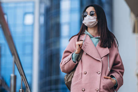 Female in medical mask outdoors in the empty city. Health protection and prevention of virus outbreak, coronavirus, COVID-19, epidemic, pandemic, infectious diseases, quarantine conceptの写真素材