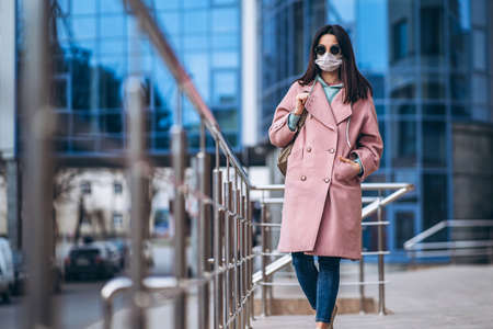 Female in medical mask outdoors in the empty city. Health protection and prevention of virus outbreak, coronavirus, COVID-19, epidemic, pandemic, infectious diseases, quarantine conceptの写真素材