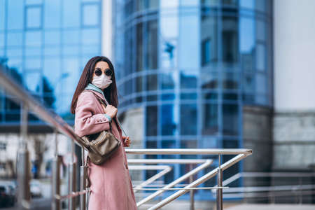 Female in medical mask outdoors in the empty city. Health protection and prevention of virus outbreak, coronavirus, COVID-19, epidemic, pandemic, infectious diseases, quarantine conceptの写真素材