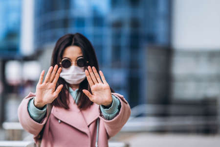 Female in medical mask outdoors in the empty city. Health protection and prevention of virus outbreak, coronavirus, COVID-19, epidemic, pandemic, infectious diseases, quarantine conceptの写真素材