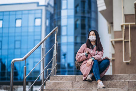 Female in medical mask outdoors in the empty city. Health protection and prevention of virus outbreak, coronavirus, COVID-19, epidemic, pandemic, infectious diseases, quarantine conceptの写真素材