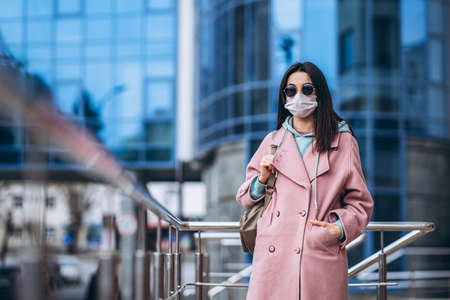 Female in medical mask outdoors in the empty city. Health protection and prevention of virus outbreak, coronavirus, COVID-19, epidemic, pandemic, infectious diseases, quarantine conceptの写真素材