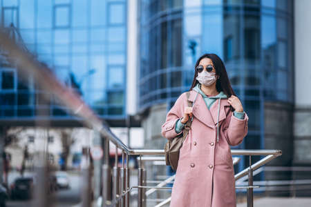 Female in medical mask outdoors in the empty city. Health protection and prevention of virus outbreak, coronavirus, COVID-19, epidemic, pandemic, infectious diseases, quarantine conceptの写真素材