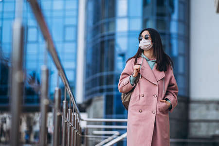 Female in medical mask outdoors in the empty city. Health protection and prevention of virus outbreak, coronavirus, COVID-19, epidemic, pandemic, infectious diseases, quarantine conceptの写真素材