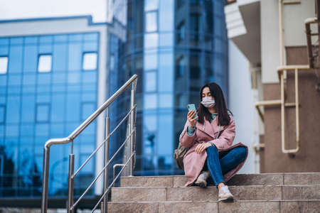 Female in medical mask outdoors in the empty city. Health protection and prevention of virus outbreak, coronavirus, COVID-19, epidemic, pandemic, infectious diseases, quarantine conceptの写真素材