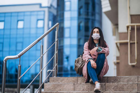 Female in medical mask outdoors in the empty city. Health protection and prevention of virus outbreak, coronavirus, COVID-19, epidemic, pandemic, infectious diseases, quarantine conceptの写真素材