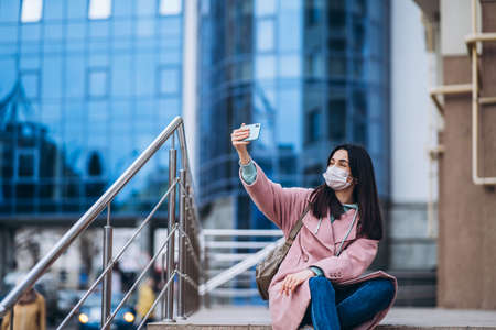Female in medical mask outdoors in the empty city. Health protection and prevention of virus outbreak, coronavirus, COVID-19, epidemic, pandemic, infectious diseases, quarantine conceptの写真素材
