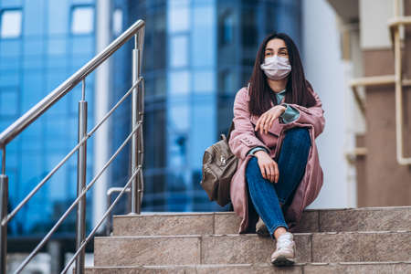 Female in medical mask outdoors in the empty city. Health protection and prevention of virus outbreak, coronavirus, COVID-19, epidemic, pandemic, infectious diseases, quarantine conceptの写真素材