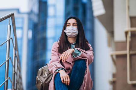 Female in medical mask outdoors in the empty city. Health protection and prevention of virus outbreak, coronavirus, COVID-19, epidemic, pandemic, infectious diseases, quarantine conceptの写真素材