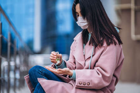 Female in medical mask outdoors in the empty city. Health protection and prevention of virus outbreak, coronavirus, COVID-19, epidemic, pandemic, infectious diseases, quarantine conceptの写真素材