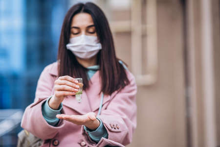 Female in medical mask outdoors in the empty city. Health protection and prevention of virus outbreak, coronavirus, COVID-19, epidemic, pandemic, infectious diseases, quarantine conceptの写真素材
