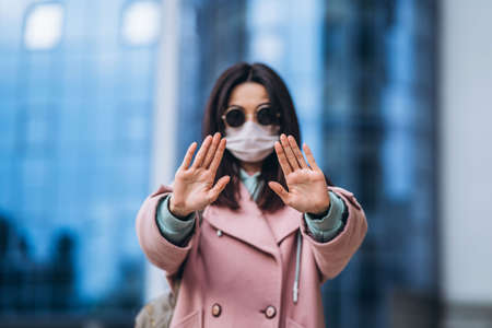 Female in medical mask outdoors in the empty city. Health protection and prevention of virus outbreak, coronavirus, COVID-19, epidemic, pandemic, infectious diseases, quarantine conceptの写真素材