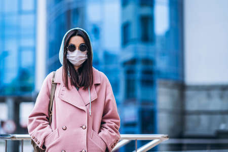 Female in medical mask outdoors in the empty city. Health protection and prevention of virus outbreak, coronavirus, COVID-19, epidemic, pandemic, infectious diseases, quarantine conceptの写真素材