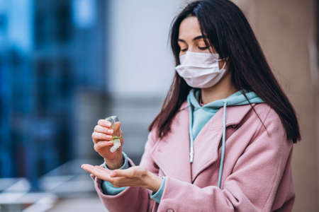 Female in medical mask outdoors in the empty city. Health protection and prevention of virus outbreak, coronavirus, COVID-19, epidemic, pandemic, infectious diseases, quarantine conceptの写真素材
