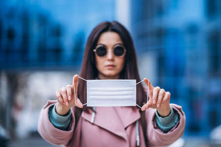Female in medical mask outdoors in the empty city. Health protection and prevention of virus outbreak, coronavirus, COVID-19, epidemic, pandemic, infectious diseases, quarantine conceptの写真素材