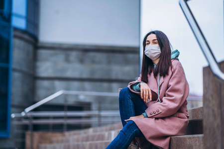 Female in medical mask outdoors in the empty city. Health protection and prevention of virus outbreak, coronavirus, COVID-19, epidemic, pandemic, infectious diseases, quarantine conceptの写真素材