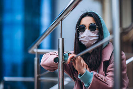 Female in medical mask outdoors in the empty city. Health protection and prevention of virus outbreak, coronavirus, COVID-19, epidemic, pandemic, infectious diseases, quarantine conceptの写真素材