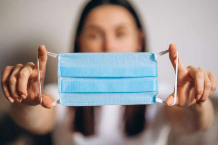 Female at home in quarantine time holding colorful protective medical masks to prevent virus disease, COVID-19, pandemic, epidemic conceptの写真素材