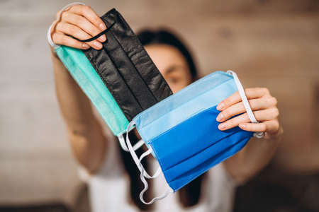 Female at home in quarantine time holding colorful protective medical masks to prevent virus disease, COVID-19, pandemic, epidemic conceptの写真素材