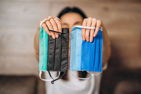 Female at home in quarantine time holding colorful protective medical masks to prevent virus disease, COVID-19, pandemic, epidemic conceptの写真素材