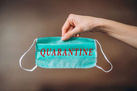 Female at home in quarantine time holding colorful protective medical masks to prevent virus disease, COVID-19, pandemic, epidemic conceptの写真素材
