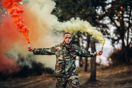 Portrait of a camouflage soldier with rifle and painted face playing airsoft outdoors in the forest. Side view.の写真素材