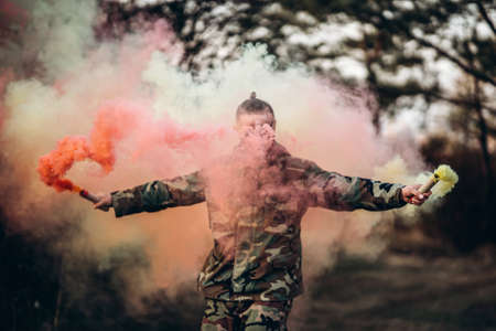 Portrait of a camouflage soldier with rifle and painted face playing airsoft outdoors in the forest. Side view.の写真素材