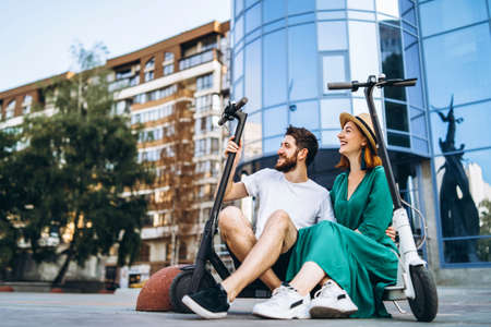 Portrait of young couple at sunset with beautiful natural landscape. Walking on electric scooters in the countryside.の写真素材