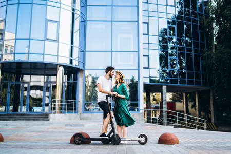 Portrait of young couple at sunset with beautiful natural landscape. Walking on electric scooters in the countryside.の写真素材