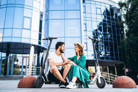 Portrait of young couple at sunset with beautiful natural landscape. Walking on electric scooters in the countryside.の写真素材