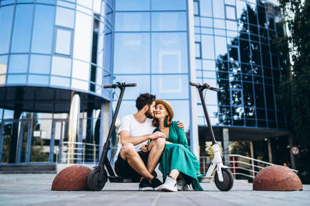 Portrait of young couple at sunset with beautiful natural landscape. Walking on electric scooters in the countryside.の写真素材