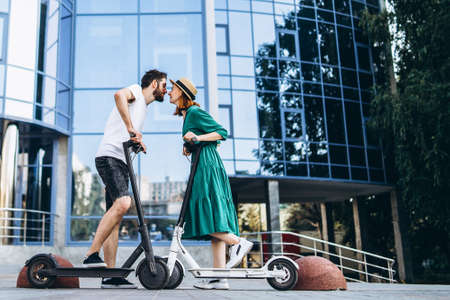 Portrait of young couple at sunset with beautiful natural landscape. Walking on electric scooters in the countryside.の写真素材