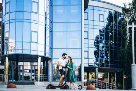 Portrait of young couple at sunset with beautiful natural landscape. Walking on electric scooters in the countryside.の写真素材