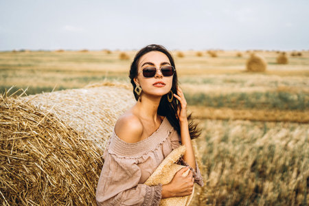 Closeup portrait of beautiful smiling woman with closed eyes. The brunette leaned on a bale of hay....